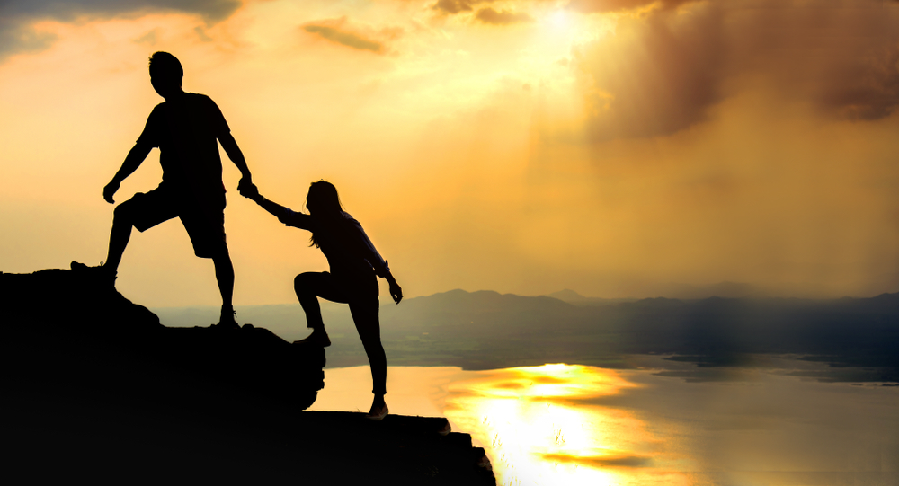 Teamwork friendship hiking help each other trust assistance silhouette in mountains, sunrise